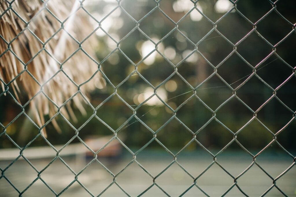 Detailed view of a chain link fence against a blurred outdoor backdrop.